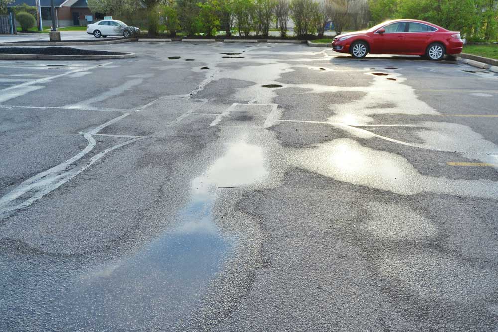 a wet asphalt parking lot, sealcoating in the rain